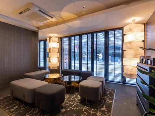 una sala de espera con sillas, mesas y grandes ventanas en Tabist kiki HOTEL KYOTO Sanjo Takakura, en Kioto