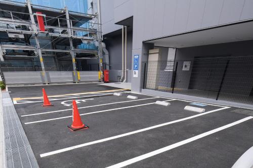 a parking lot with orange cones in front of a building at Vessel Inn Takadanobaba Station in Tokyo