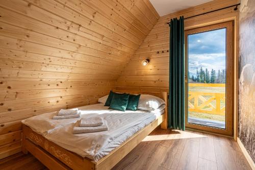 a bed in a wooden room with a window at Domki Tatrzański Przystanek in Białka Tatrzanska