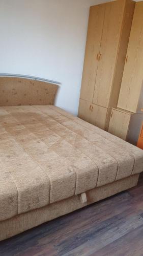 a bed in a room with two wooden cabinets at Apartman Lami in Tuzla