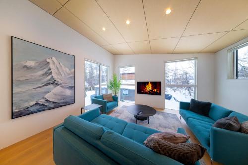 a living room with blue couches and a fireplace at Blue River Chalets by The Hakuba Collection in Hakuba