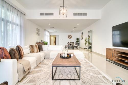 een woonkamer met een bank en een tafel bij Lavish 4BR Villa with 2 Assistant Rooms, Al Dana Island, Fujairah by Deluxe Holiday Homes in Fujairah