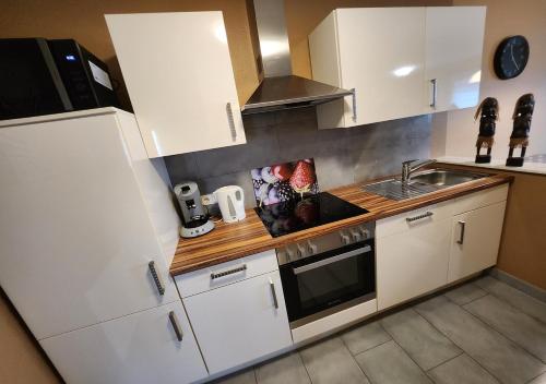 a small kitchen with white cabinets and a sink at Ferienwohnungen Abendsonne - 8 Gehminuten zum EP in Rust