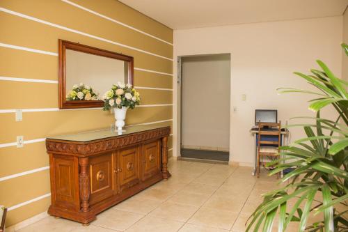 a hallway with a mirror and a dresser with flowers on it at Pousada Cataratas in Foz do Iguaçu
