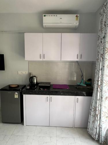 Una cocina con gabinetes blancos y una encimera negra. en Azure : Private Studio in Koregaon Park, en Pune