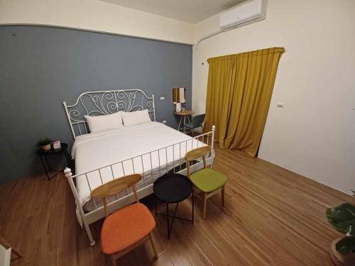 ein Schlafzimmer mit einem Bett und Stühlen in einem Zimmer in der Unterkunft 舟津食旅 Mooring B&B 禁菸民宿 訂房請詳閱住宿須知 in Hualien