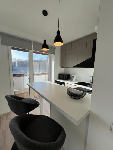 a kitchen with a white table and two black chairs at Mugavustega korter pargi serval in Jõhvi
