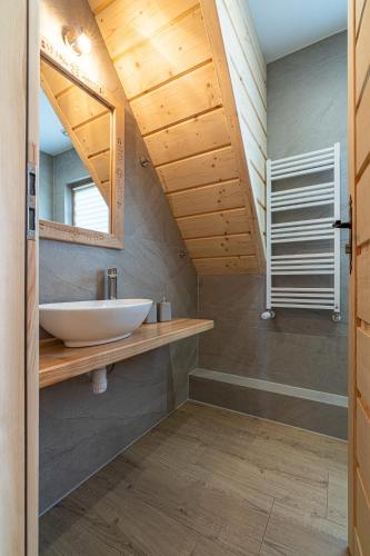 a bathroom with a sink and a wooden ceiling at Domki Tatrzański Przystanek in Białka Tatrzanska