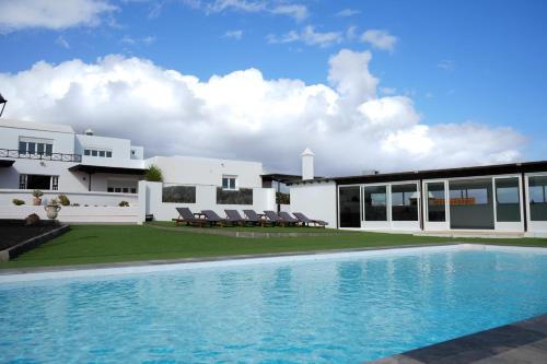 una casa con piscina frente a ella en Renovated Villa Mahalo with swimming pool & tennis court en Tías