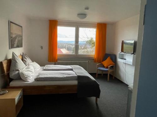 een slaapkamer met een bed en een raam met oranje gordijnen bij Doppelzimmer mit Albblick in Tübingen