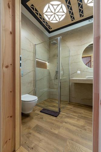 a bathroom with a toilet and a glass shower at Domki Tatrzański Przystanek in Białka Tatrzanska