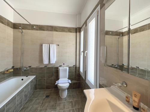a bathroom with a toilet and a tub and a sink at Villa Seagull in Skala Kefalonias