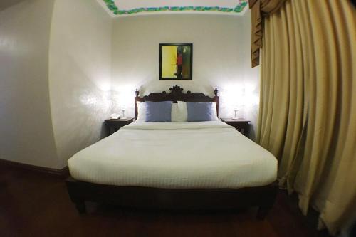 a bedroom with a bed with white sheets and blue pillows at NSCC Hotel Vigan in Vigan