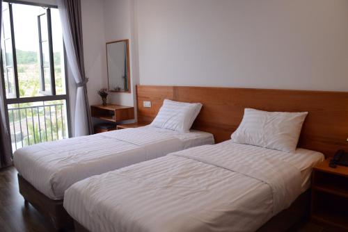 duas camas num quarto de hotel com uma janela em Sunrise Hotel em Phu Quoc