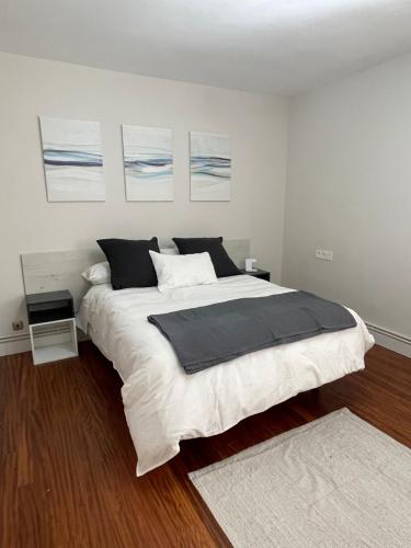a bedroom with a large bed and some paintings on the wall at Apartamento Ideal in Mundaka