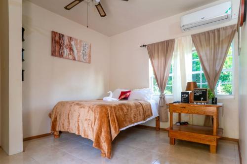 a bedroom with a bed and a table and a window at Eleven30 Luxury Apartment 2B in Negril