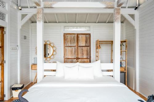 a white bedroom with a white bed with white pillows at Mambo Hill Resort in Nusa Penida