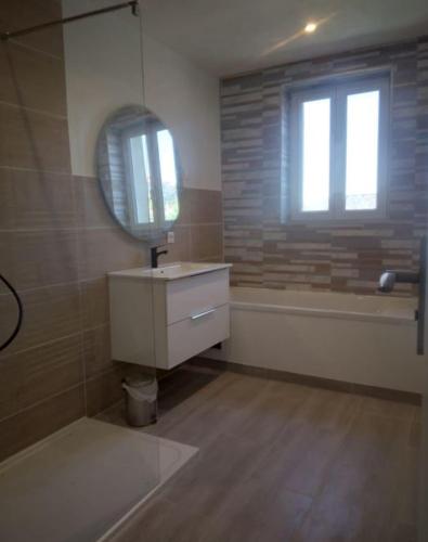 une salle de bain avec une baignoire, un lavabo et un miroir dans l'établissement Maison au centre de Cahors, à Cahors