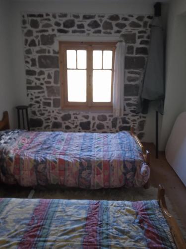 a bedroom with two beds in front of a stone wall at Stone house cottage in Sígrion