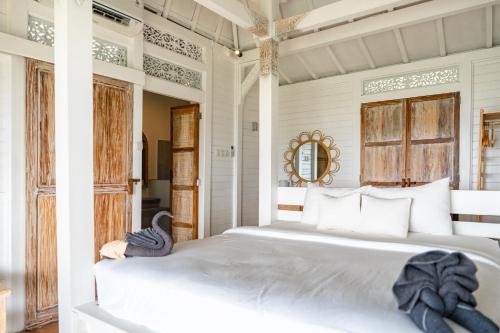 a bedroom with a large white bed with white pillows at Mambo Hill Resort in Nusa Penida
