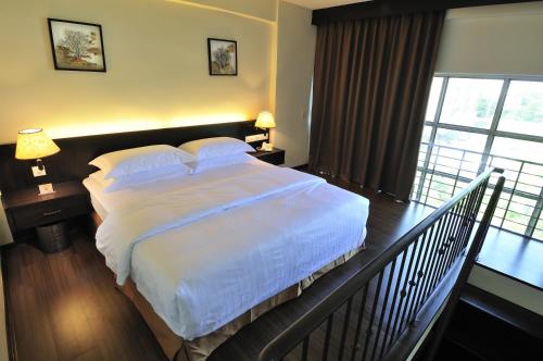 a bedroom with a bed with white sheets and a balcony at ERNES Hotel in Perai
