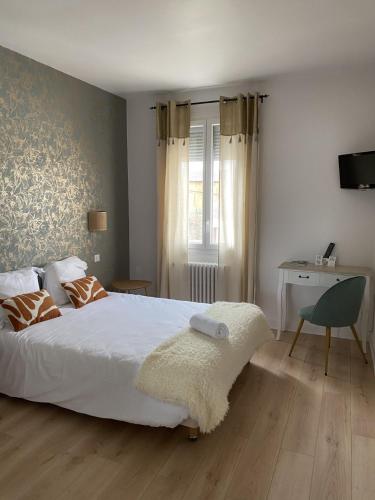 a bedroom with a large white bed and a desk at Hôtel Aux Vendanges de Bourgogne in Paray-le-Monial