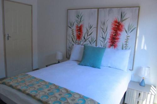 a bedroom with a white bed with blue and red pillows at Gaborone 1 bed suburban bliss in Gaborone