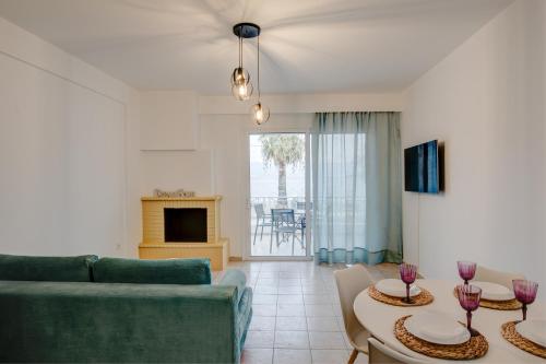 a living room with a couch and tables and a tv at Sugar Blue - Apartments on the beach in Áyios Vasílios