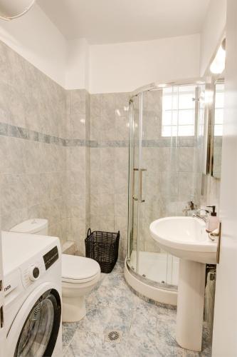 a bathroom with a toilet a sink and a washing machine at Seaside Apartments in Áyios Vasílios