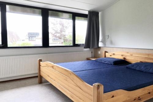 a bedroom with a wooden bed with blue sheets and windows at De Woning, Wijk de Brabander 109 in Cadzand