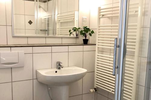 a white bathroom with a sink and a mirror at De Woning, Wijk de Brabander 109 in Cadzand