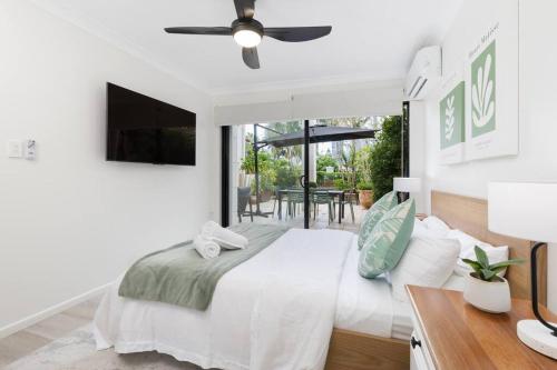 um quarto branco com uma cama e uma ventoinha de tecto em Spacious 2 Bed/2 Bath Garden Apartment Aircon em Brisbane