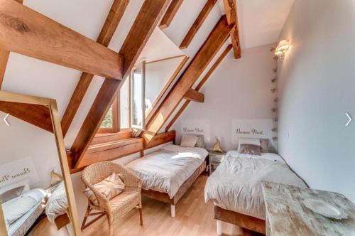 sypialnia na poddaszu z 2 łóżkami i stołem w obiekcie Le gite de la tour w mieście Bressieux