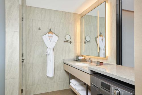 a bathroom with a sink and a shower with a robe at Courtyard by Marriott Changchun in Changchun