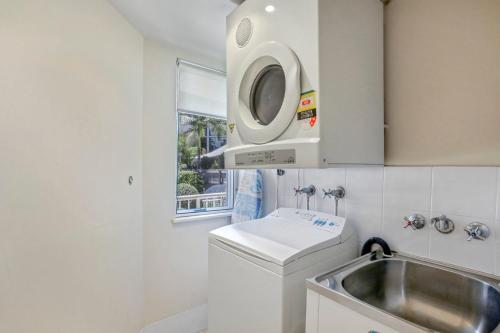 een keuken met een wastafel en een wasmachine bij Ocean Vista On Alex in Alexandra Headland