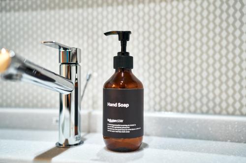 a bottle of hand soap sitting on a bathroom sink at Rakuten STAY Kokura Station in Kitakyushu
