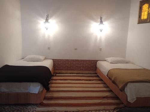 2 Betten in einem Zimmer mit Wandbeleuchtung in der Unterkunft Dar Es Salam in Skoura