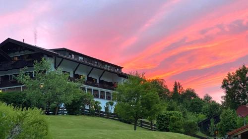 a building with a sunset in the background at Gästehaus Hotel Maria Theresia - Kennenlernpreise für den Frühling am Schliersee in Schliersee