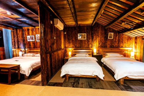 a group of four beds in a room with wooden walls at Lost World Sanjiang Guest house in Sanjiang
