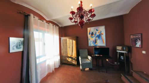 a living room with a chandelier and a chair and a window at Hotel Utopía in Benalup Casas Viejas