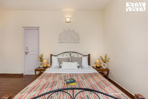 a bedroom with a large bed with white walls at StayVista at Bird's Crest Valley Villa in Rāmgarh