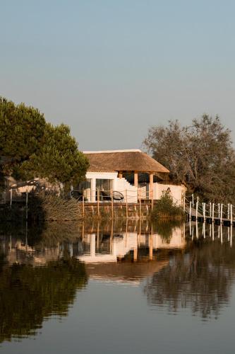 a house sitting on the side of a body of water at Mas de la Fouque - Hôtel & Spa in Saintes-Maries-de-la-Mer
