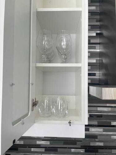 a white cabinet with wine glasses in it at Gifty Surprize Airbnb in Kimberley