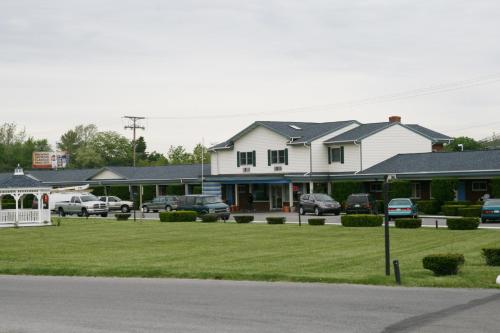 una gran casa blanca con coches aparcados en un aparcamiento en WYE Motor Lodge Duncansville - Altoona, en Duncansville