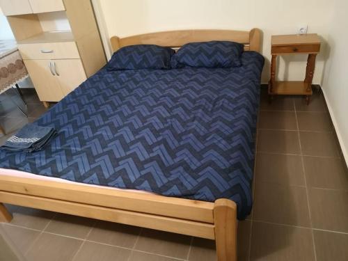 a bed with a blue comforter in a room at Cozy apartment for short term rent. in Kać
