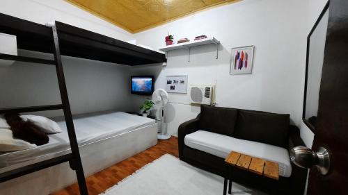 een slaapkamer met een stapelbed en een bank bij 1BR or 2BR Staycation in Quezon City 5 in Manilla
