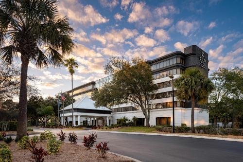 a building with a palm tree in front of a street at Delta Hotels by Marriott Jacksonville Deerwood in Jacksonville