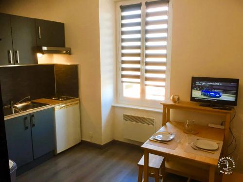 une petite cuisine avec une table et une fenêtre dans l'établissement Gîte Studio Les Oliviers, à Narbonne