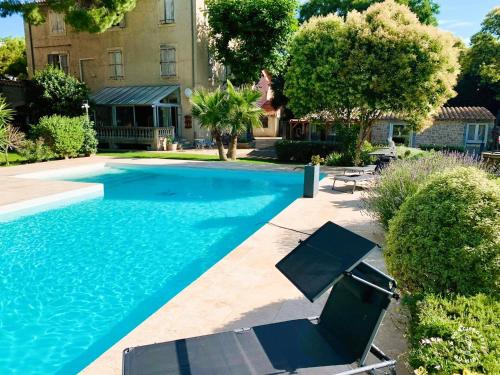- une piscine avec 2 chaises à côté d'un bâtiment dans l'établissement Gîte Studio Les Oliviers, à Narbonne