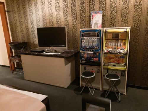 a room with a refrigerator and a computer monitor and stools at グッドホテル大阪 大人専用 in Toyonaka
